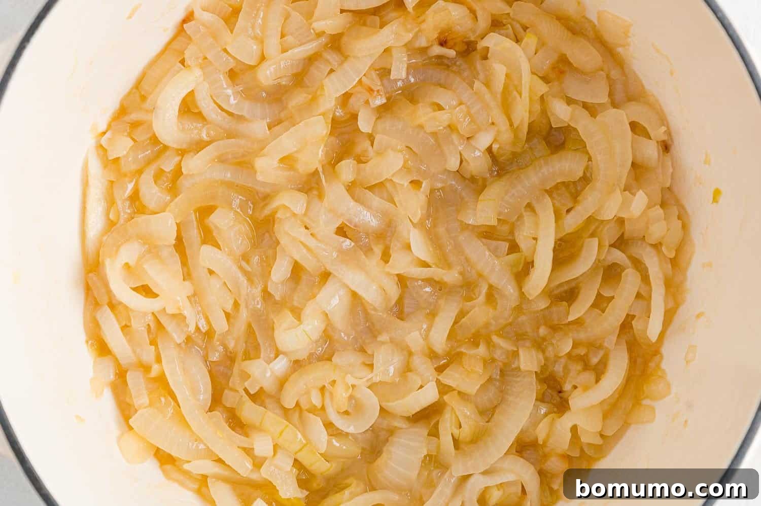 Partially cooked onions in a Dutch oven, softened and beginning to reduce in volume.