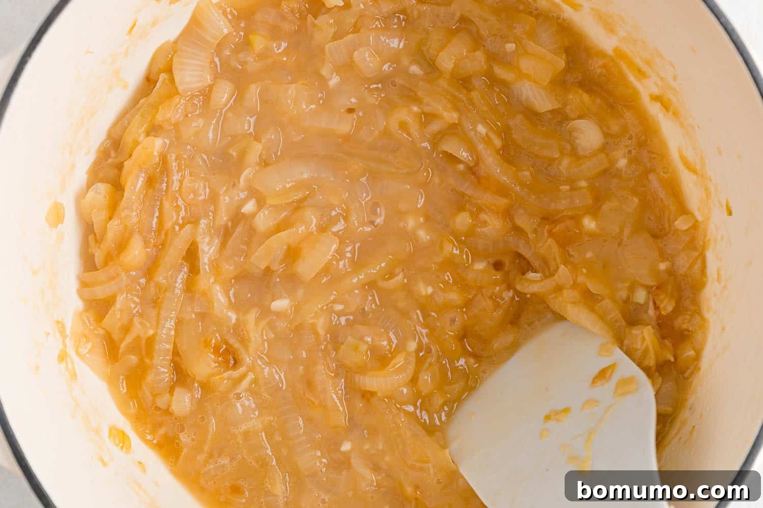 Caramelized onions with flour, butter, and sherry being added to the pan.