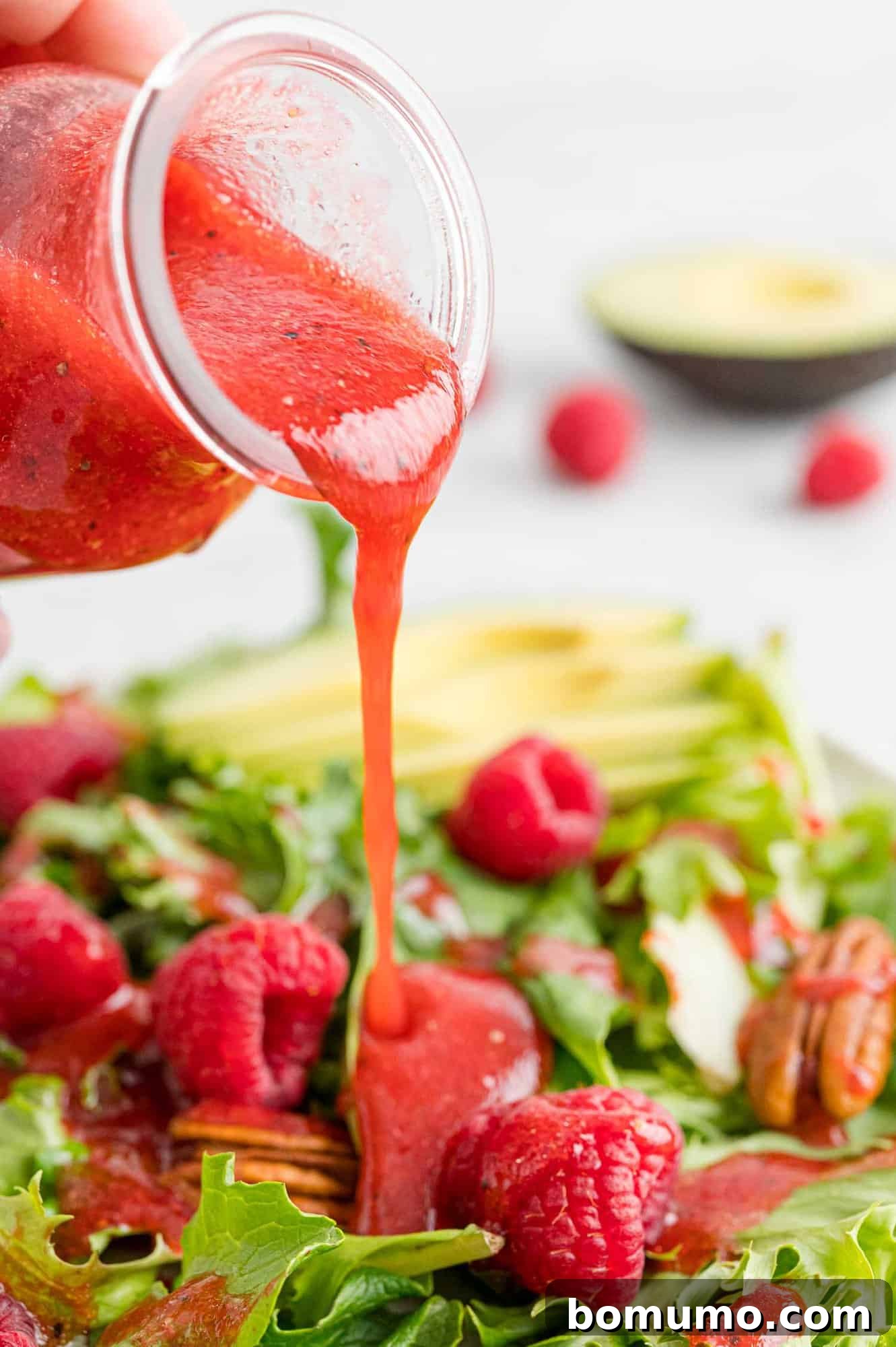 Vinaigrette dressing being poured on a fresh, vibrant salad, highlighting its rich color and appetizing texture.