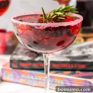 A Love Potion Cocktail, beautifully garnished with a sprig of rosemary and fresh berries, ready to be enjoyed.