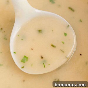 Make ahead turkey gravy in a white ladle.
