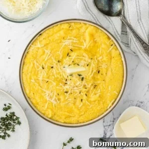 Instant pot polenta in a serving bowl with butter and thyme, ready to be enjoyed.