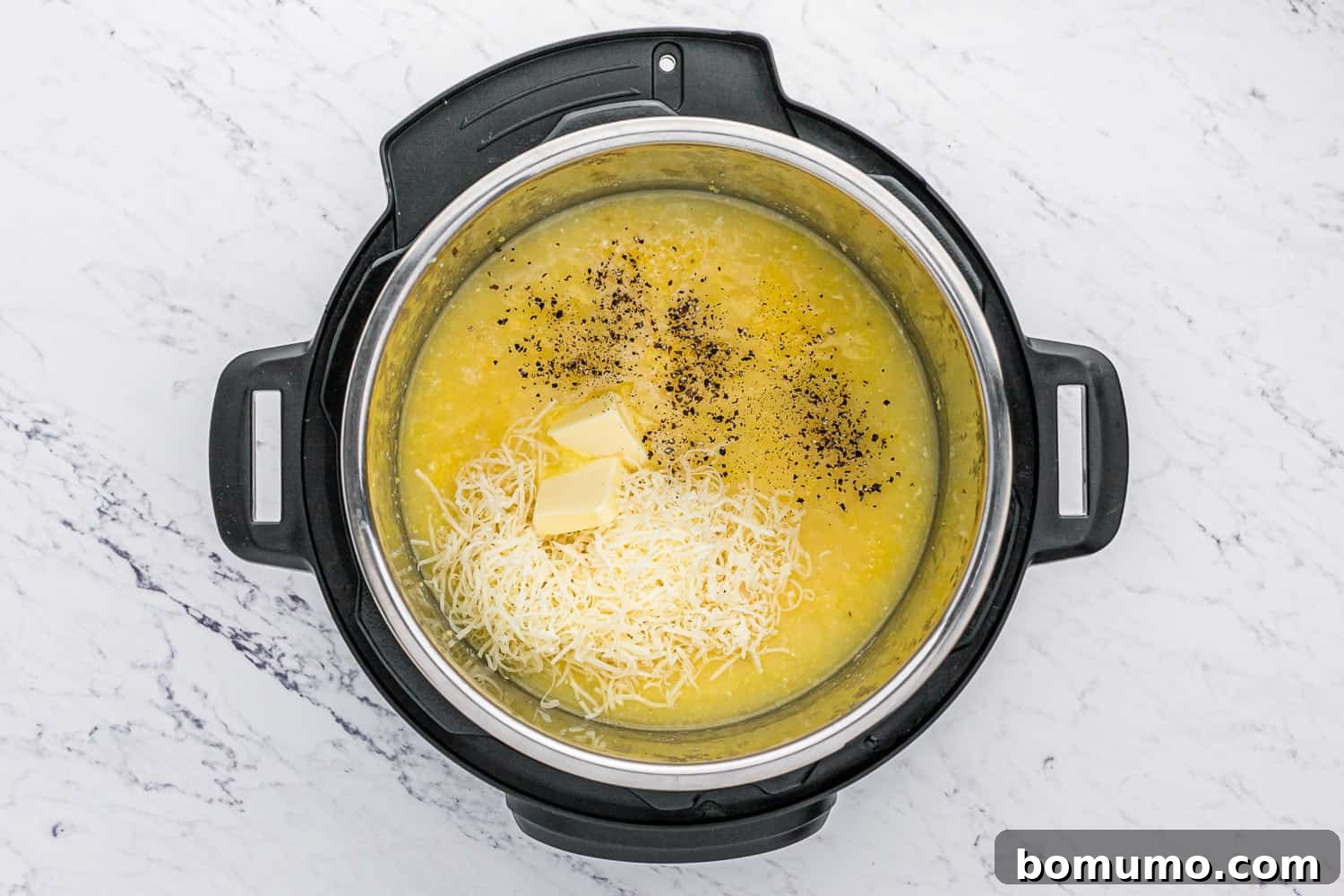 Butter, cheese, and pepper ready to be stirred into the freshly cooked Instant Pot polenta.