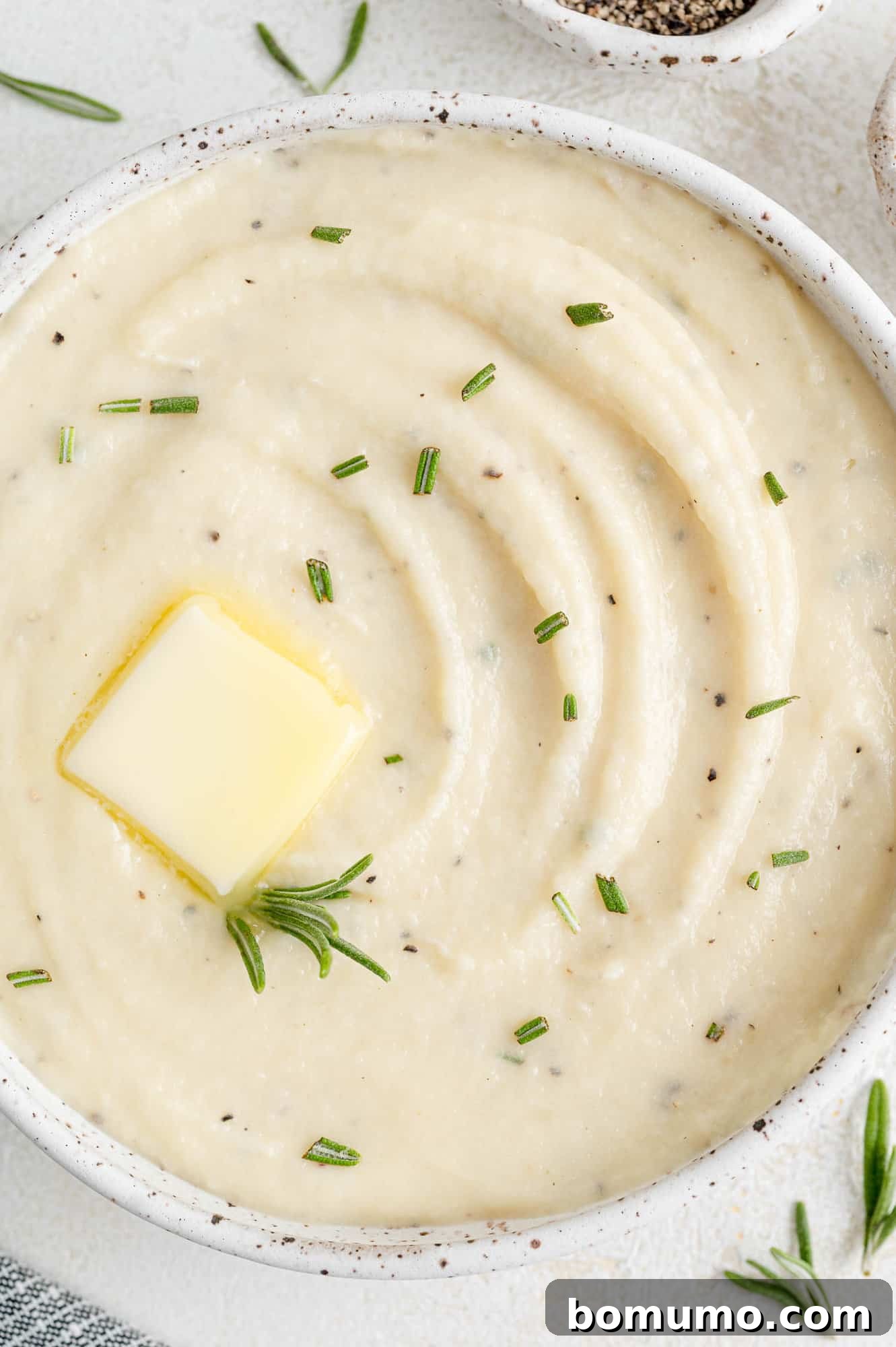 Silken Parsnip Puree 3 Parsnip puree in a white glass bowl garnished with butter and rosemary.
