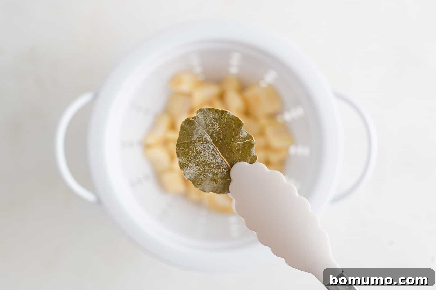 Silken Parsnip Puree 9 Bay leaf being removed from cooked parsnips.
