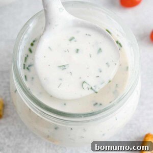 Healthy ranch dressing in a small ladle held over a jar.