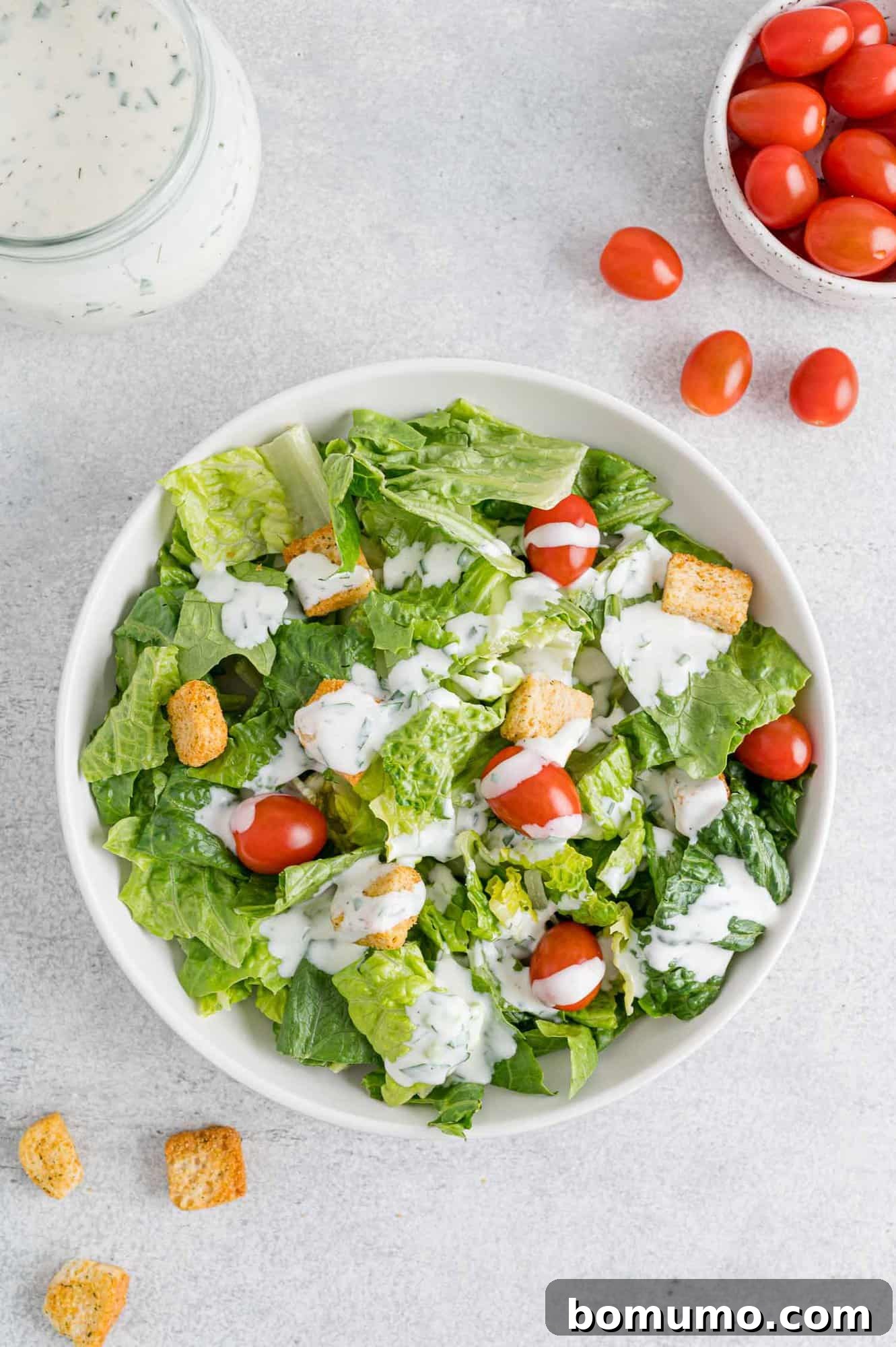 A vibrant salad featuring crisp romaine lettuce, cherry tomatoes, homemade croutons, and a generous drizzle of healthy ranch dressing.