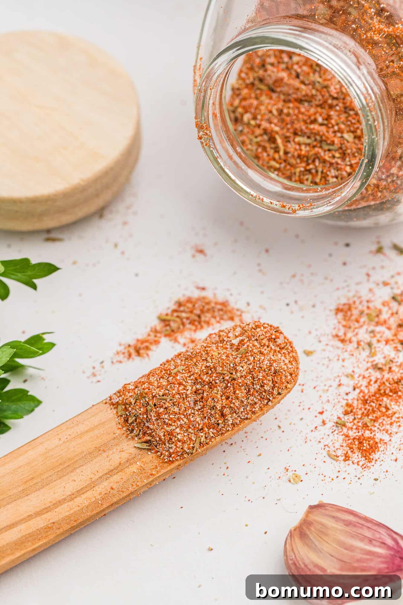 Cajun Spice Blend 2 Cajun seasoning on a small wooden spoon and spilling out of a jar.