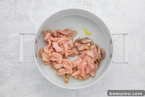 Sliced and seasoned chicken breast in a pan, ready for browning.