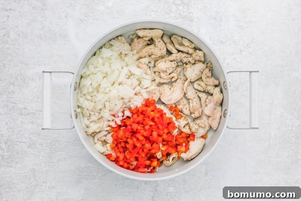 Diced bell peppers and onions added to the pan with browned chicken.