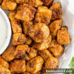 Crispy chicken bites on a plate with ranch dressing.