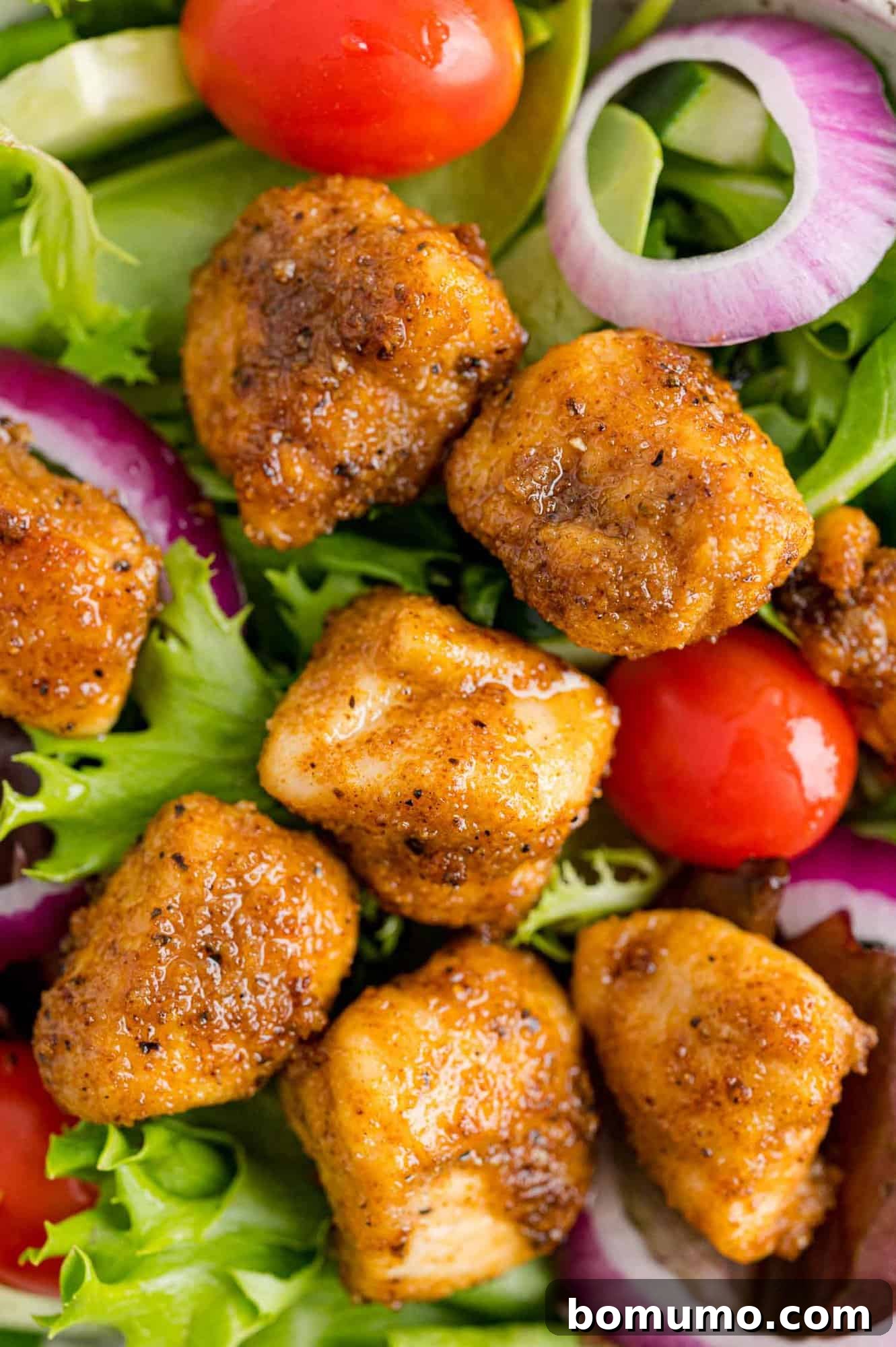 Golden Chicken Bites 3 Crispy chicken bites beautifully arranged on a fresh, vibrant tossed green salad.