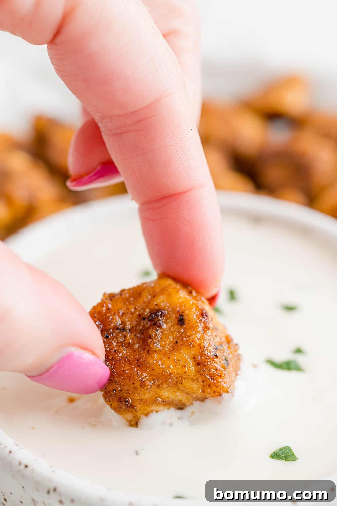 Golden Chicken Bites 9 A close-up shot of a crispy chicken bite being dipped into a creamy white ranch dressing.
