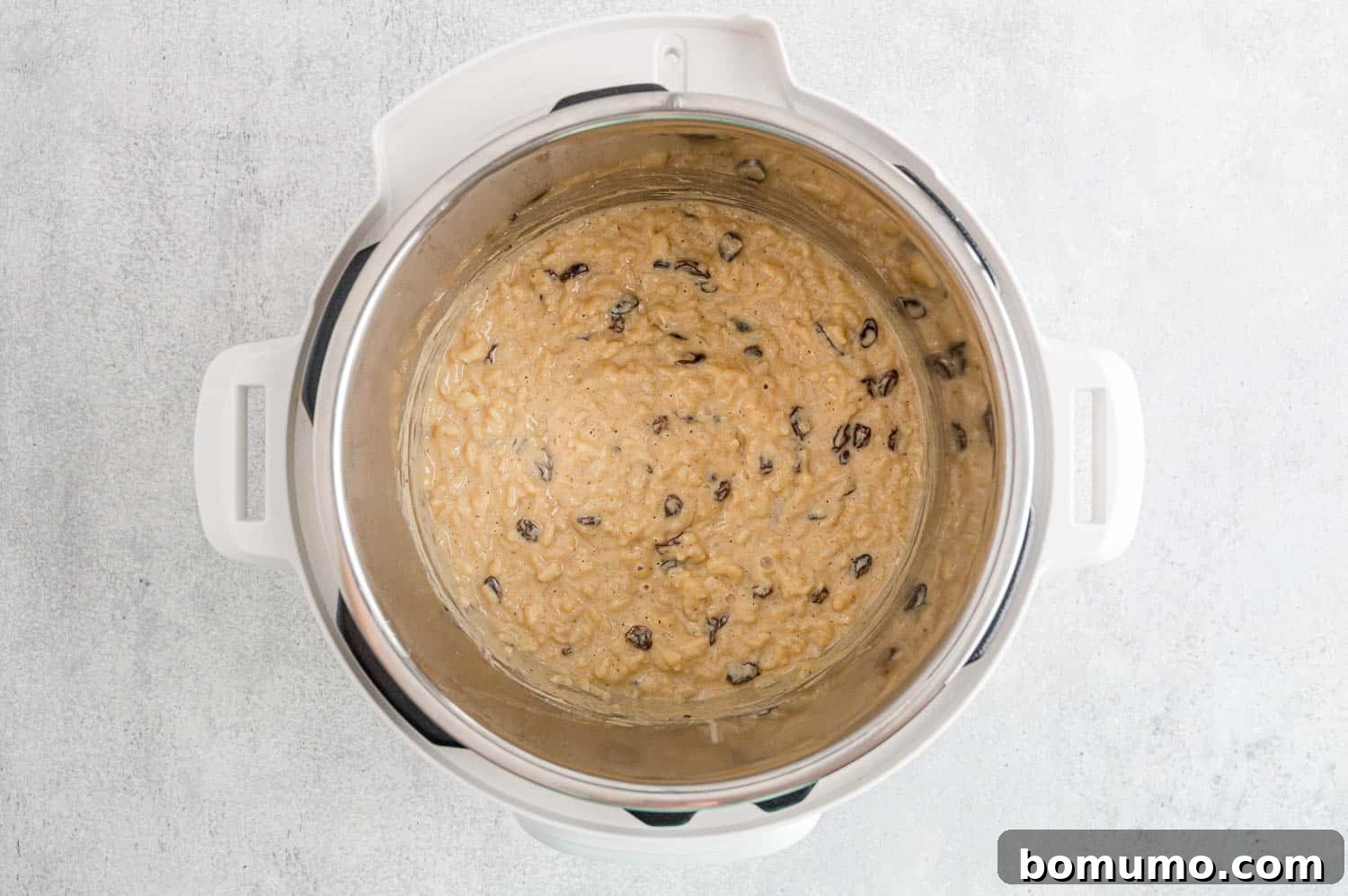 Raisins being stirred into the finished Instant Pot rice pudding.