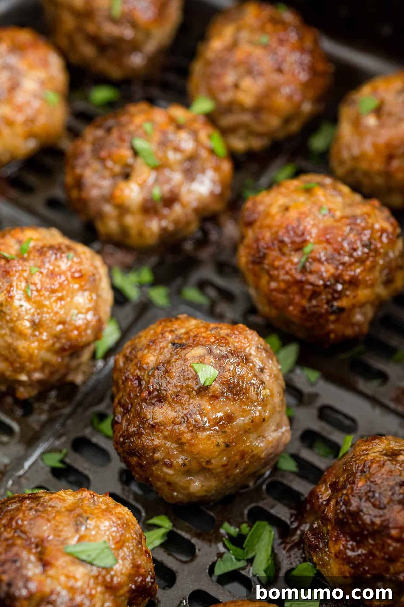 Golden-brown meatballs nestled in an air fryer basket, ready to be served.
