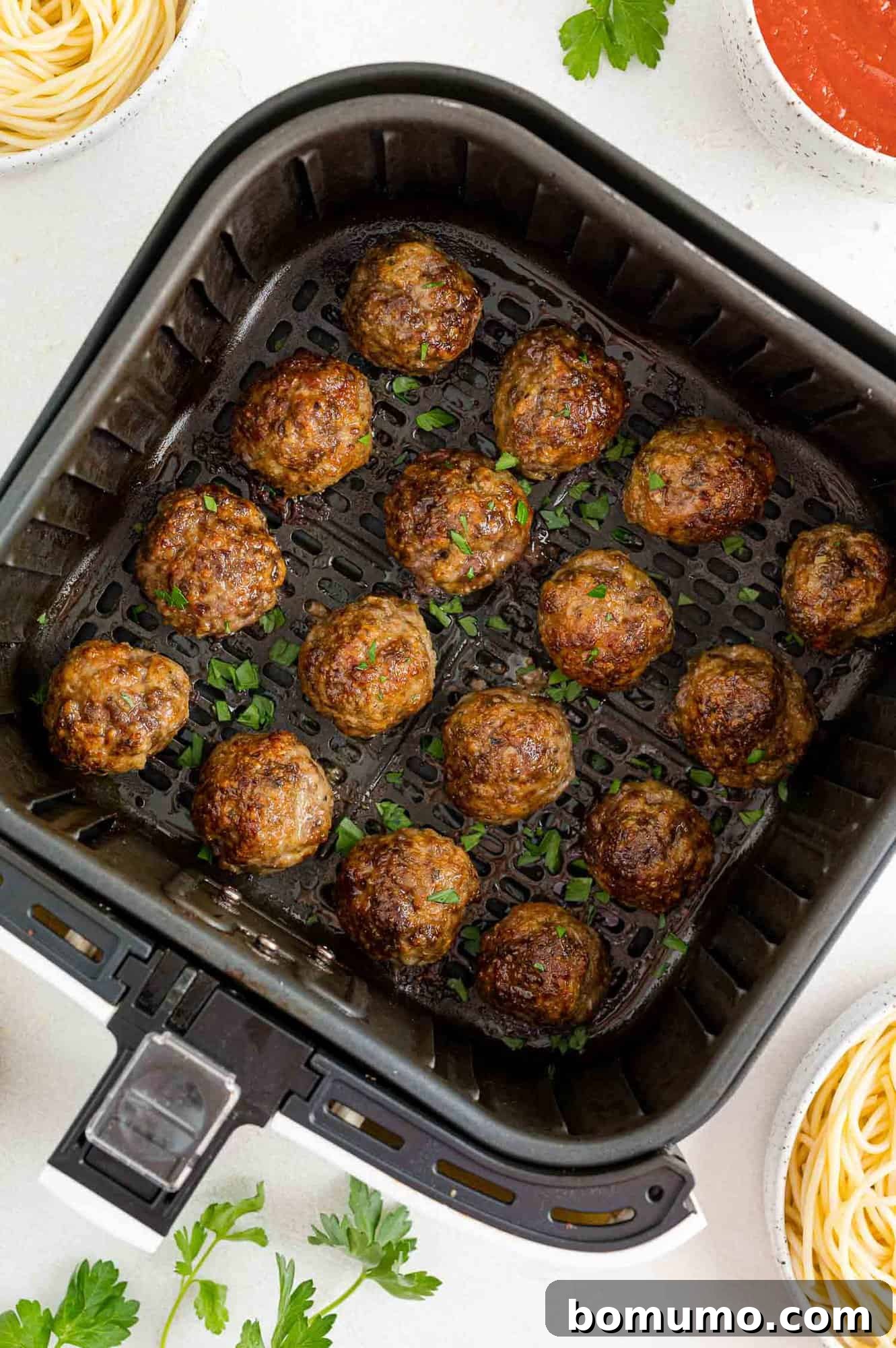 Perfectly cooked and browned meatballs inside the air fryer basket, ready to be removed.