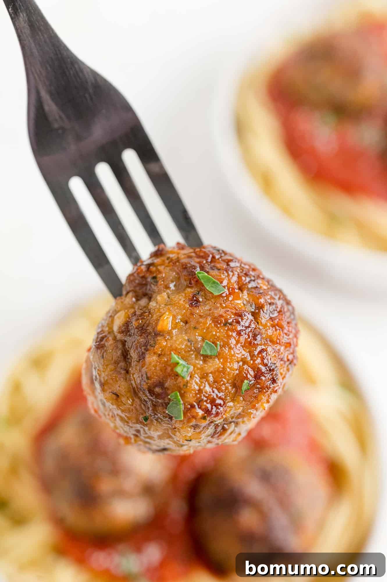 A perfectly browned air-fried meatball on a fork, showcasing its crispy exterior and tender interior.