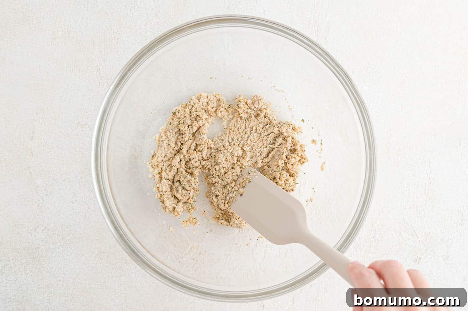Breadcrumbs soaking in milk in a mixing bowl, creating a panade for the meatballs.
