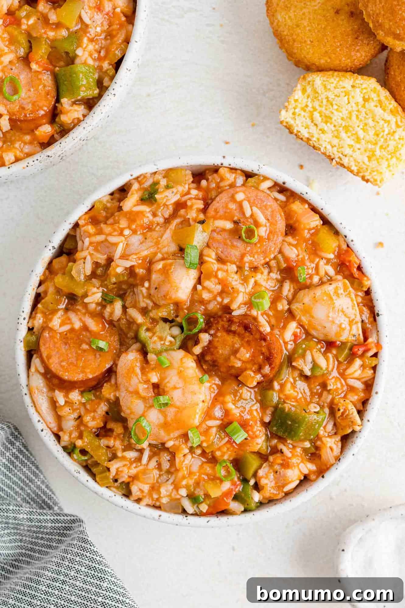Jambalaya in serving bowl with corn muffins.