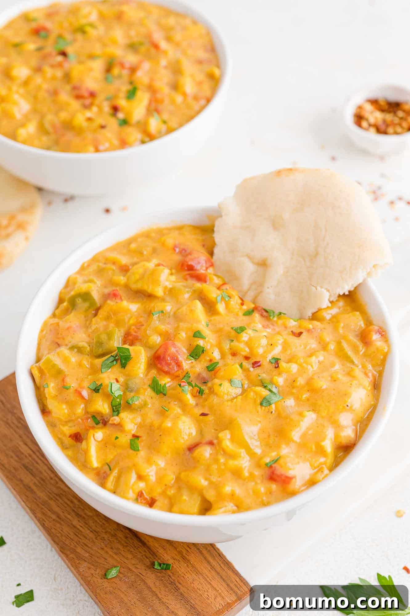 Mulligatawny soup in a bowl with naan bread on the side.