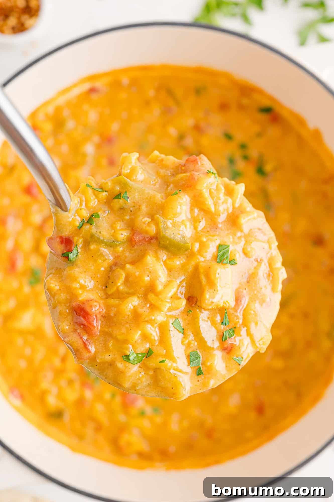 Yellow toned soup on a ladle, showcasing its rich texture.