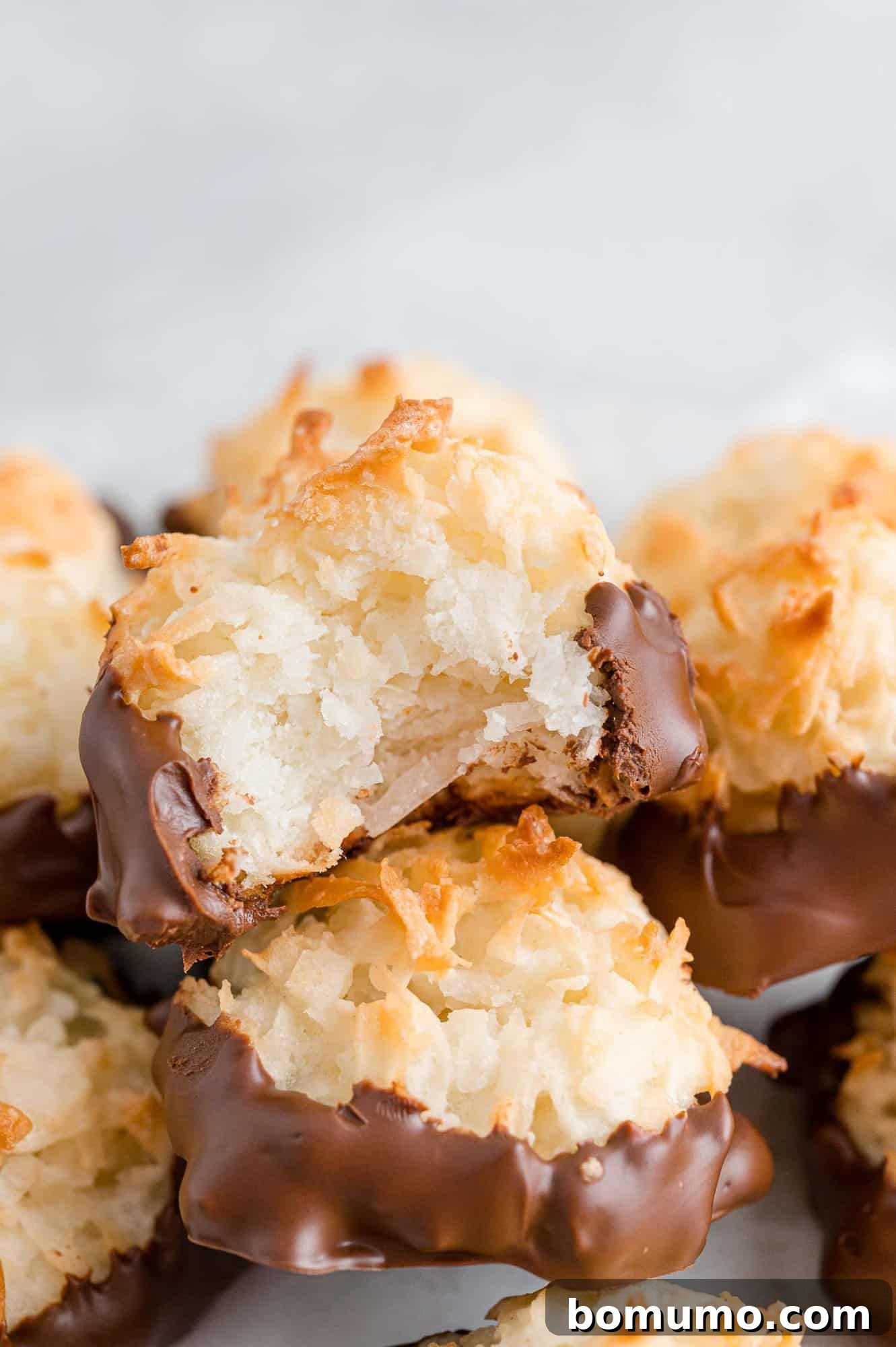 Chewy Coconut Delights 2 A tantalizing pile of golden-brown coconut macaroons, with one showcasing a perfect bite taken, revealing its moist, chewy interior.