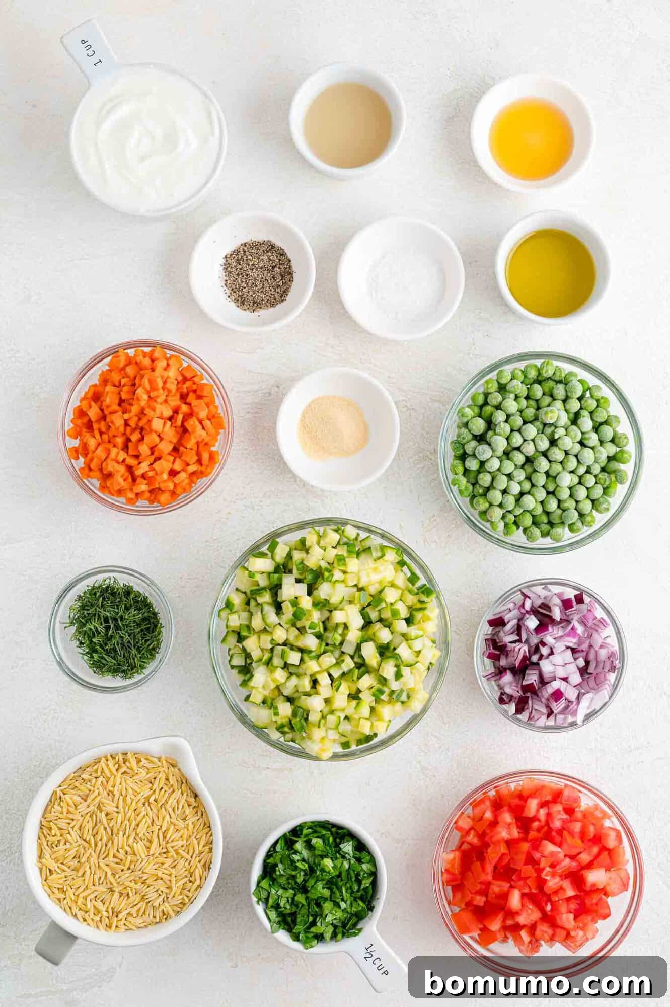 Overhead flat lay of all fresh ingredients required for the orzo salad and its yogurt dill dressing, neatly arranged.