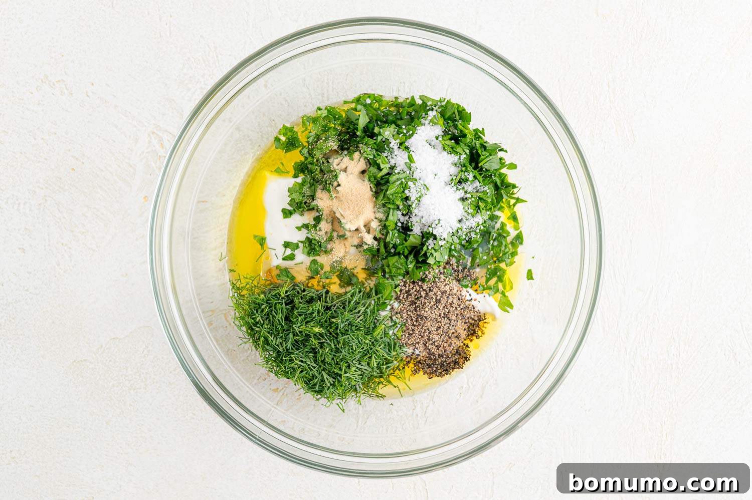 Individual dressing ingredients, including yogurt, olive oil, lemon juice, and herbs, arranged before mixing.