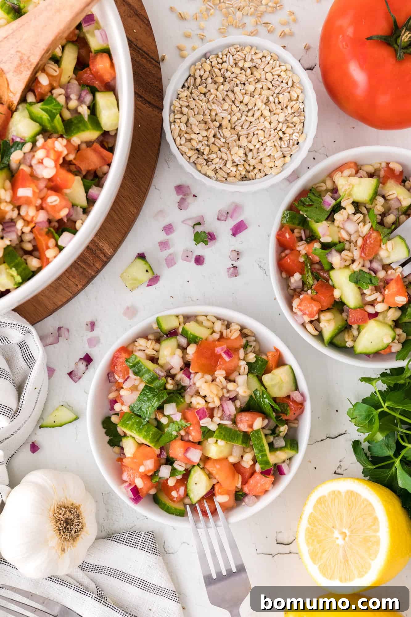 Multiple bowls of barley salad, with fresh ingredients nearby.