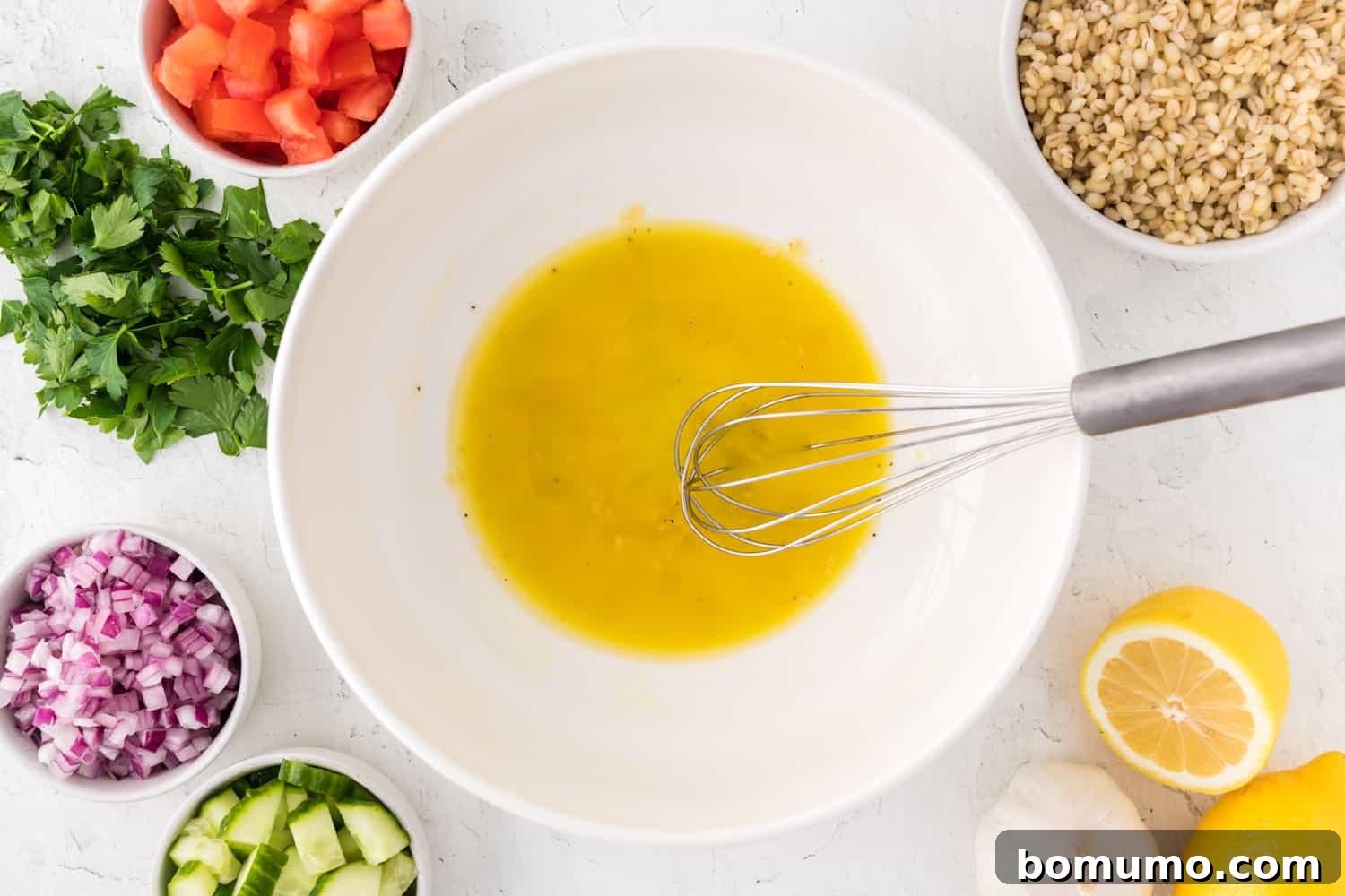 Dressing, whisked together. Other salad ingredients near by.
