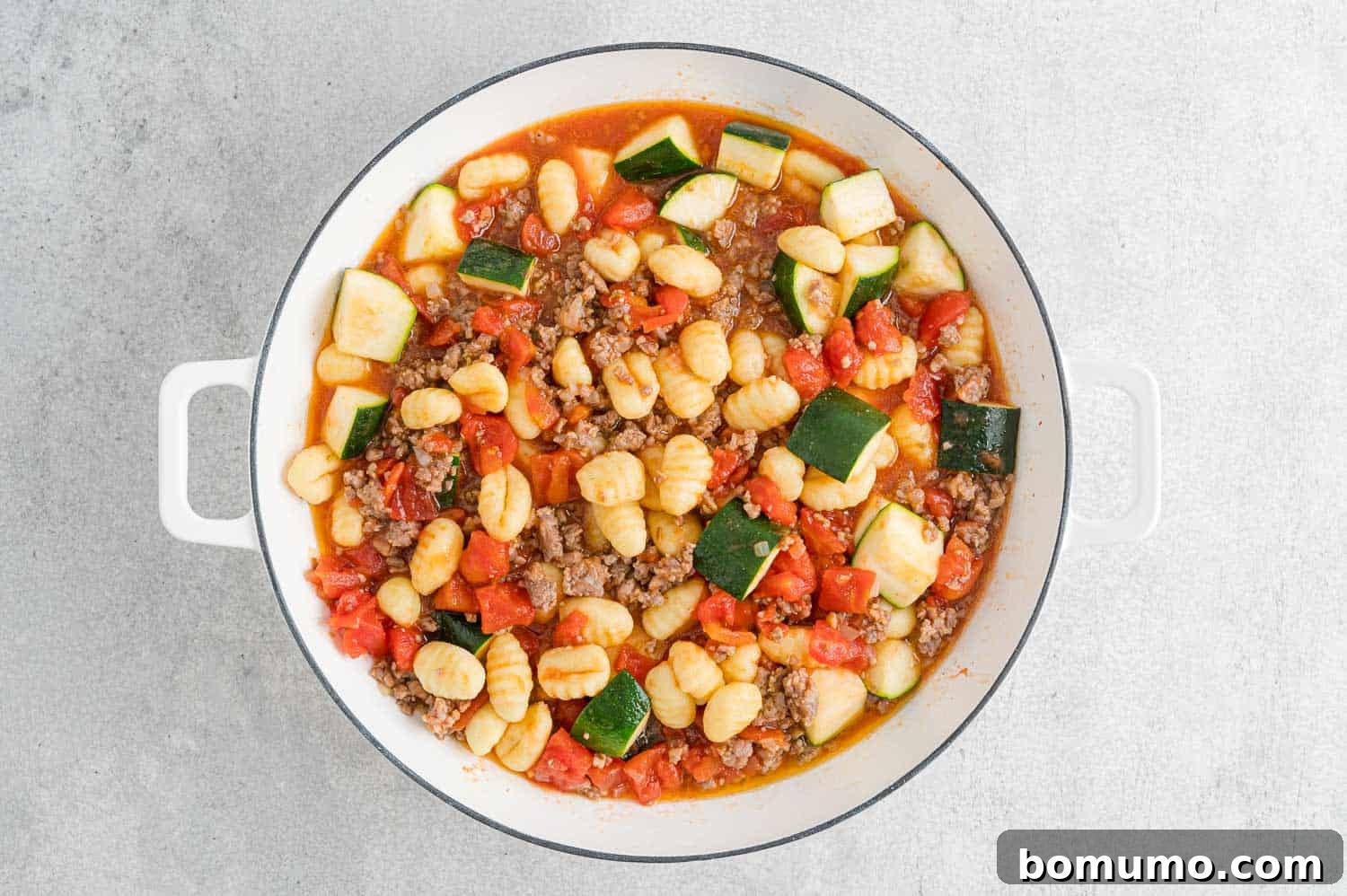 Potato gnocchi added to the simmering tomato and sausage mixture in the pan.