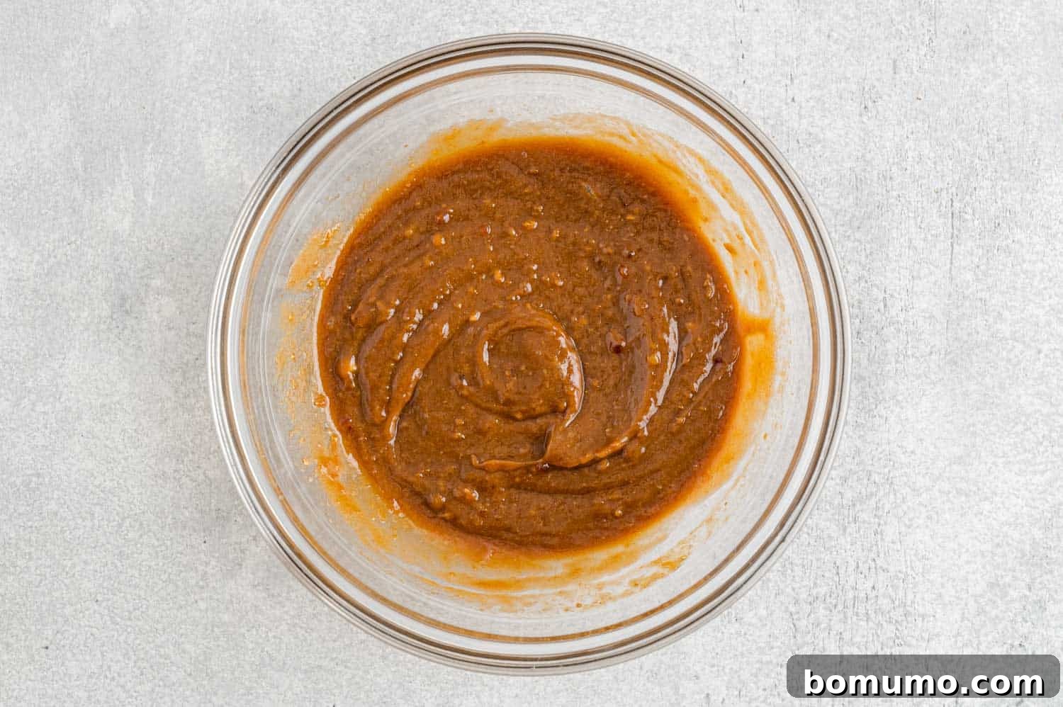 A small bowl containing a perfectly smooth, rich peanut sauce, ready to be drizzled over the cooked ingredients.