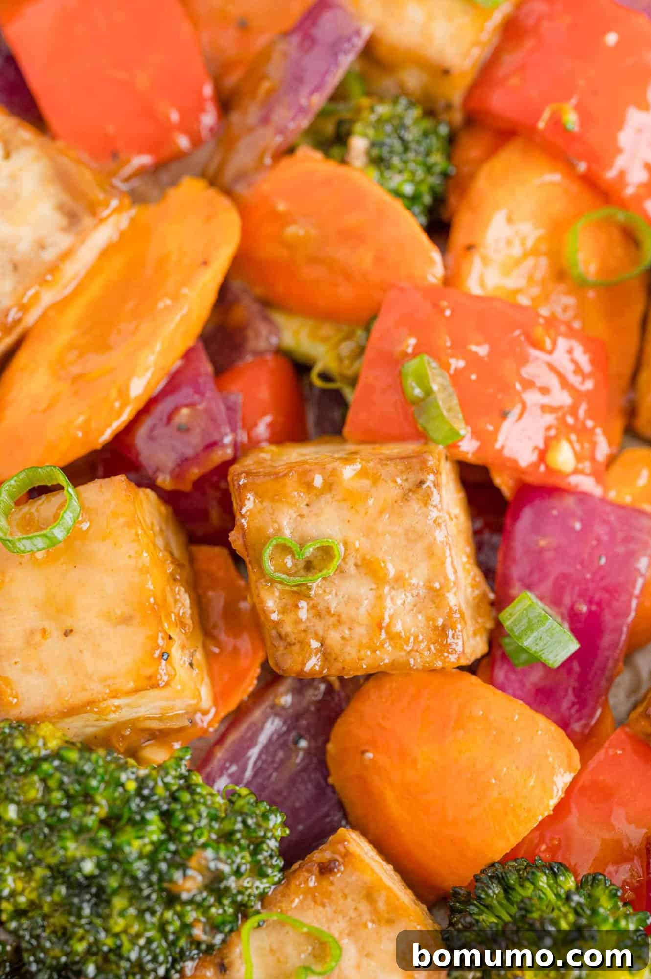 A mouth-watering close-up of tofu and vegetables generously coated with creamy peanut butter sauce, presented beautifully for serving.