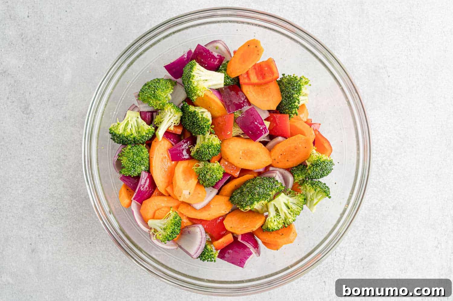 A generous quantity of colorful vegetables, thoroughly tossed with olive oil and seasonings, spread evenly on a sheet pan.
