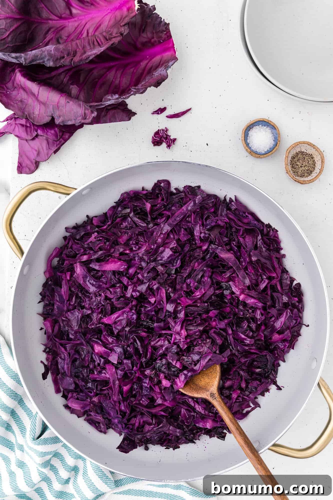 Sautéed red cabbage simmering gently in a large skillet, displaying its rich purple color and tender texture.