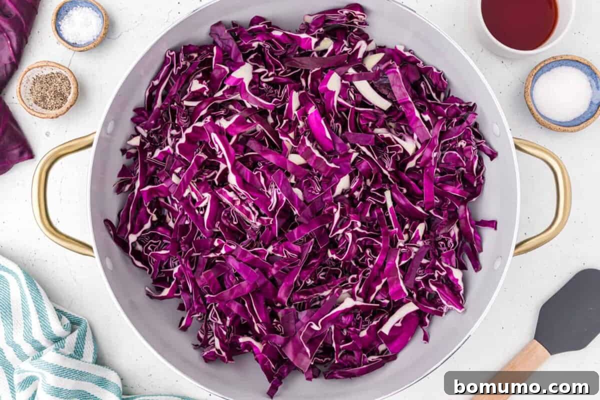 Thinly sliced, uncooked red cabbage glistening in a large skillet, ready for sautéing.