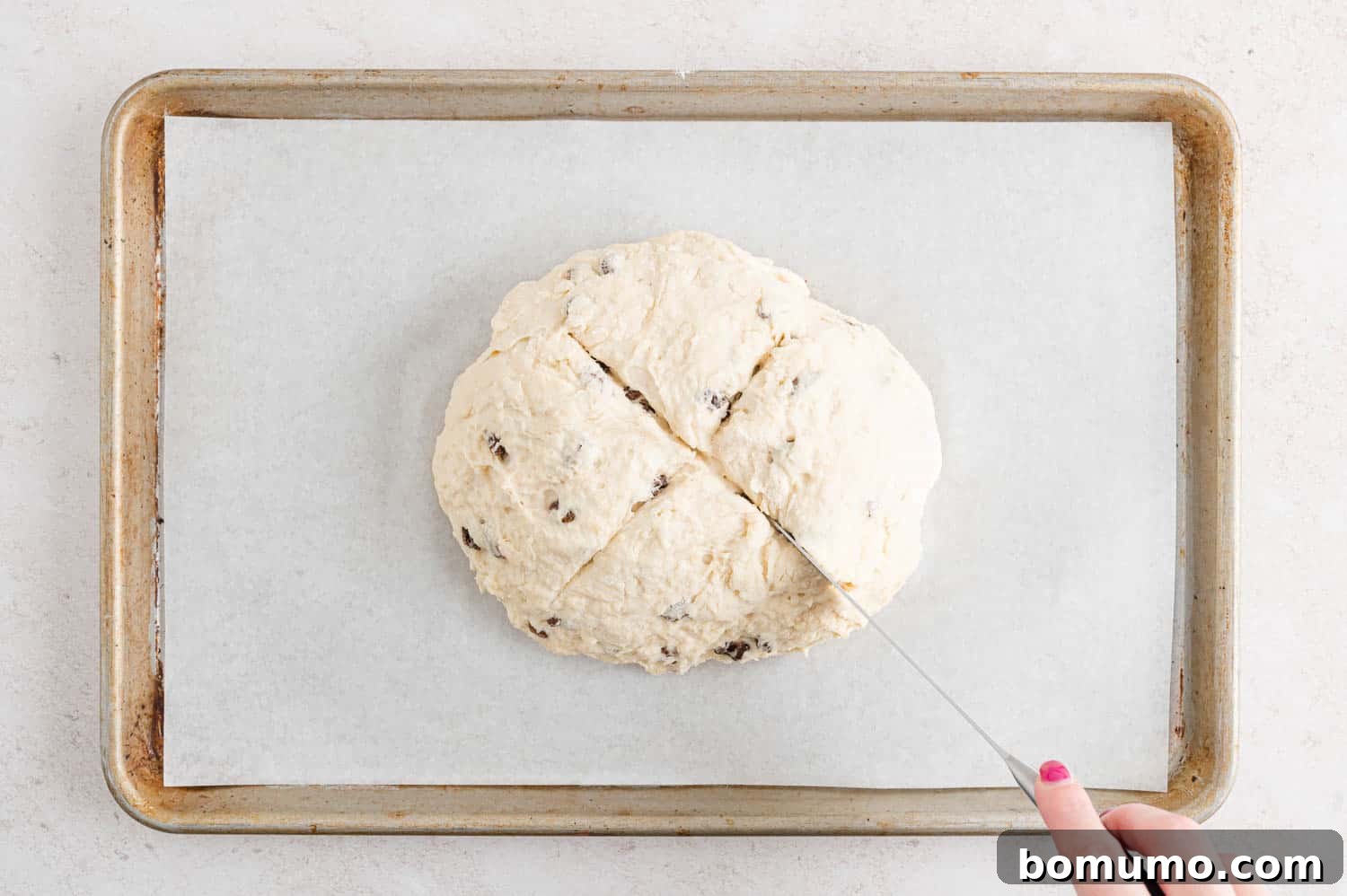 Irish soda bread dough being scored with an X-shape on top.