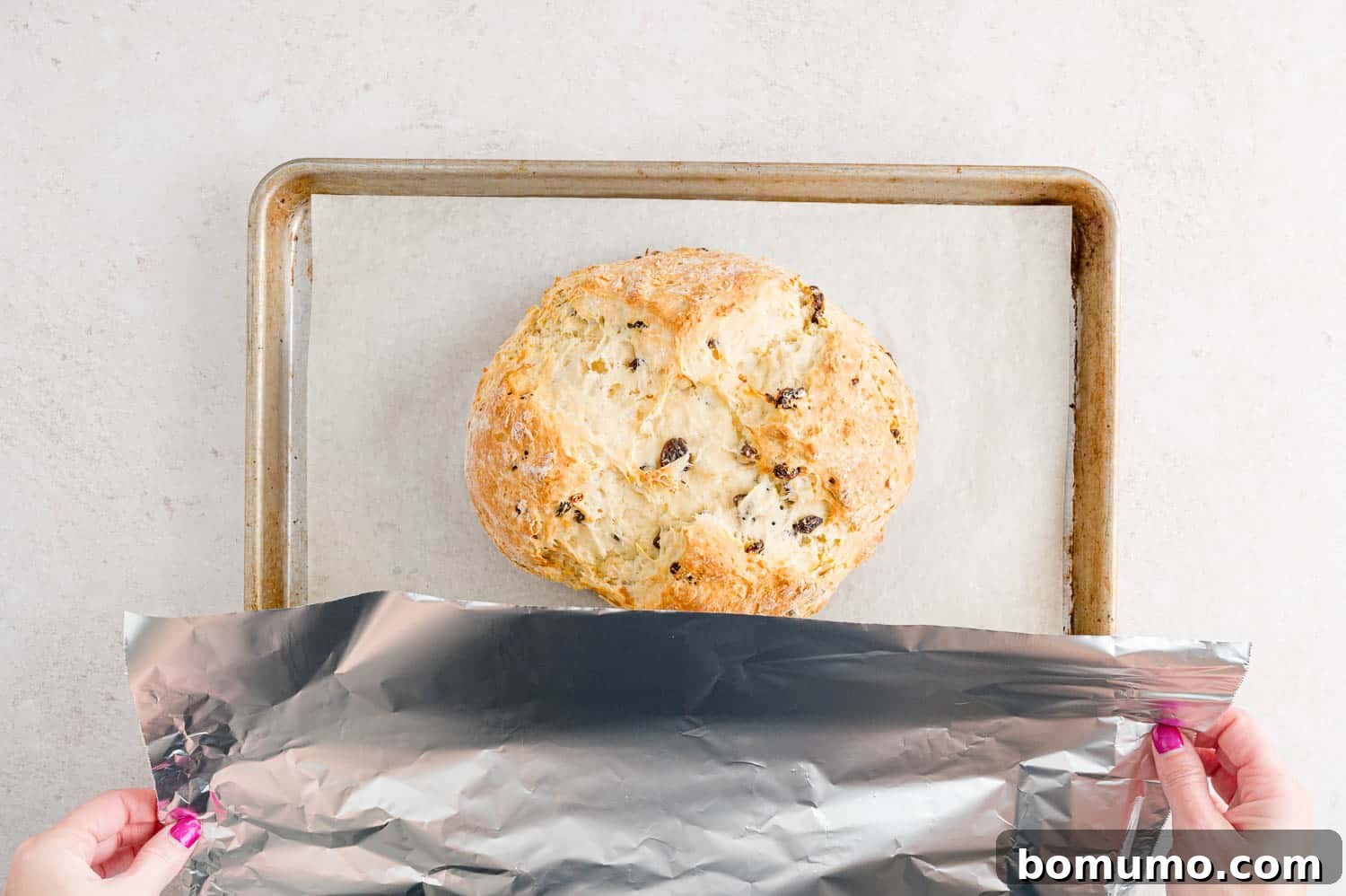 Irish soda bread being covered loosely with foil during baking to prevent over-browning.