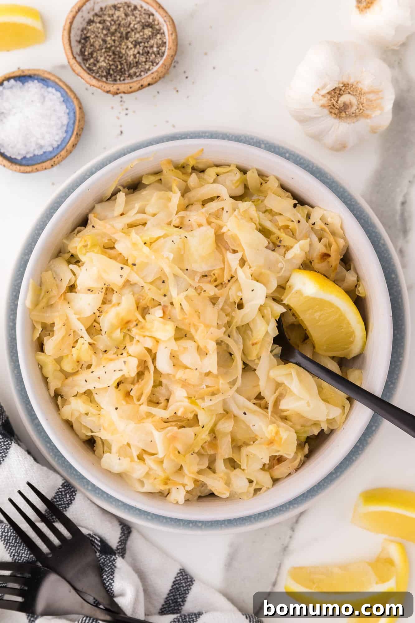 Sautéed Cabbage Reimagined 2 Sautéed cabbage in a large bowl with lemon wedges.