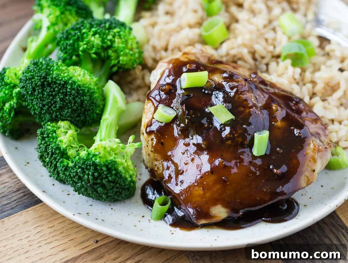 Chicken high with shiny glaze on a plate with broccoli.
