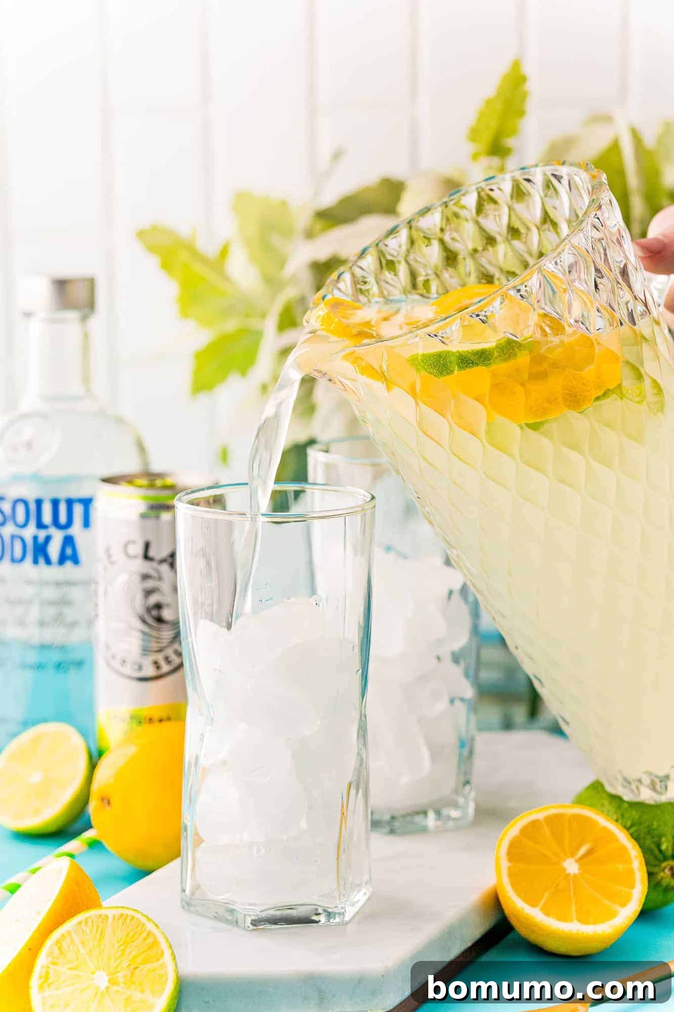 Lemonade being poured into a glass from a large glass pitcher.