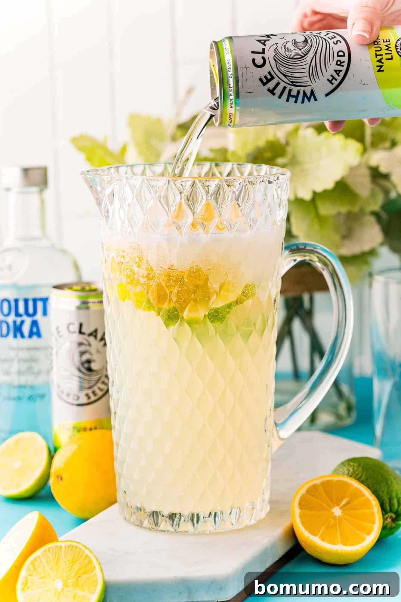 A can of White Claw being poured into a large pitcher already containing lemonade and other ingredients, creating a vibrant punch.