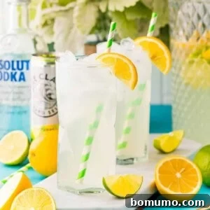 Two glasses of vodka lemonade garnished with orange wedges.