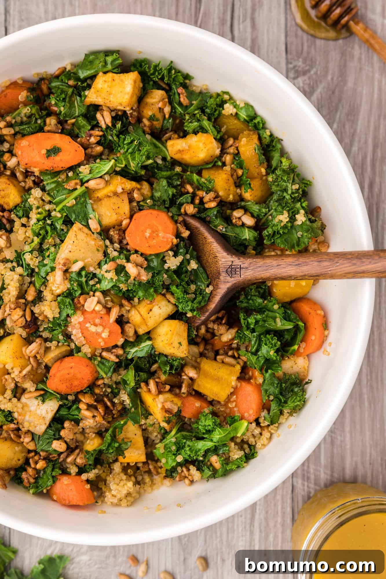 A vibrant warm kale salad featuring roasted root vegetables and quinoa, ready to be served.