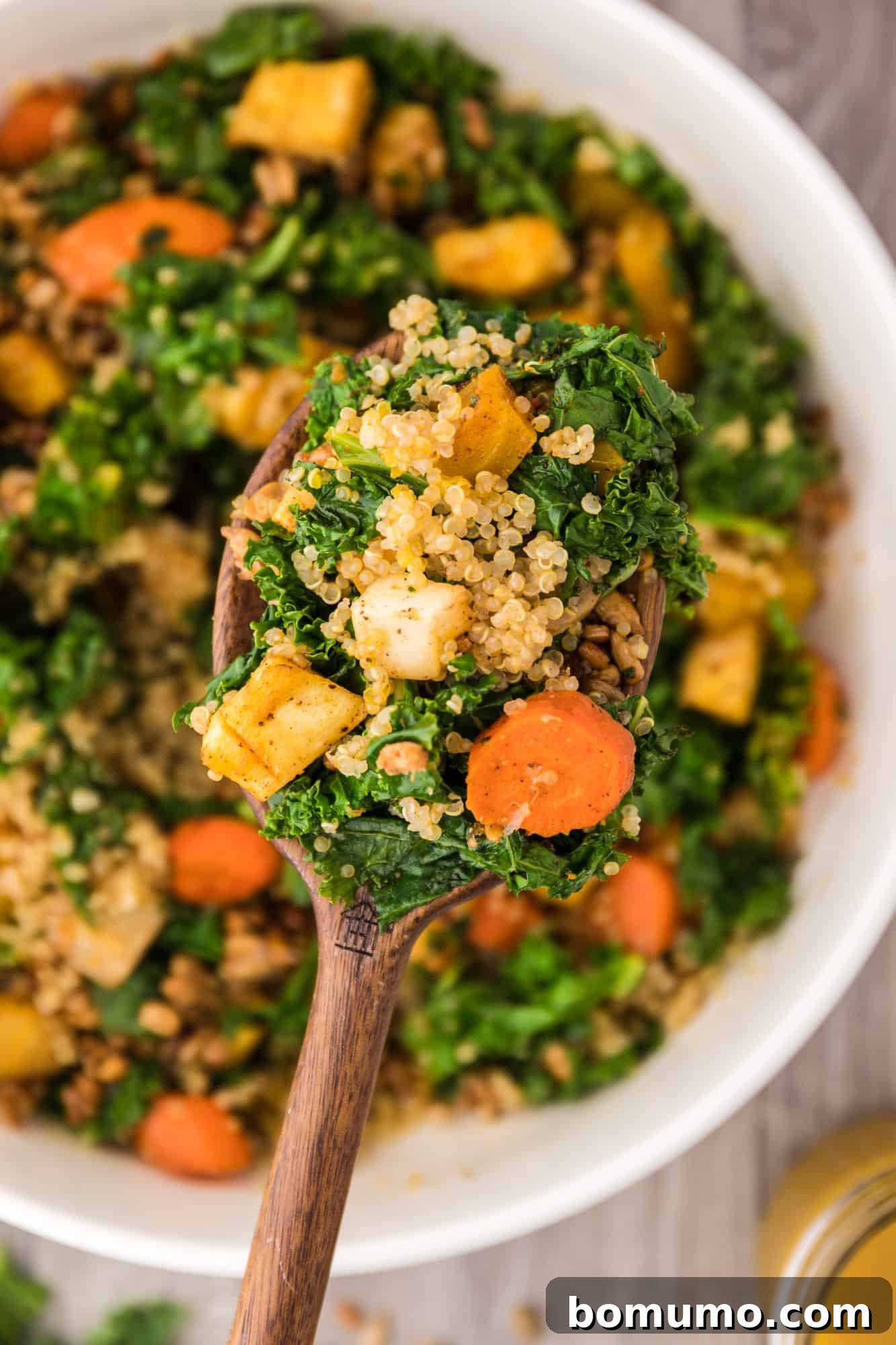 A spoonful of warm kale salad showcasing the roasted vegetables, quinoa, and vibrant greens.