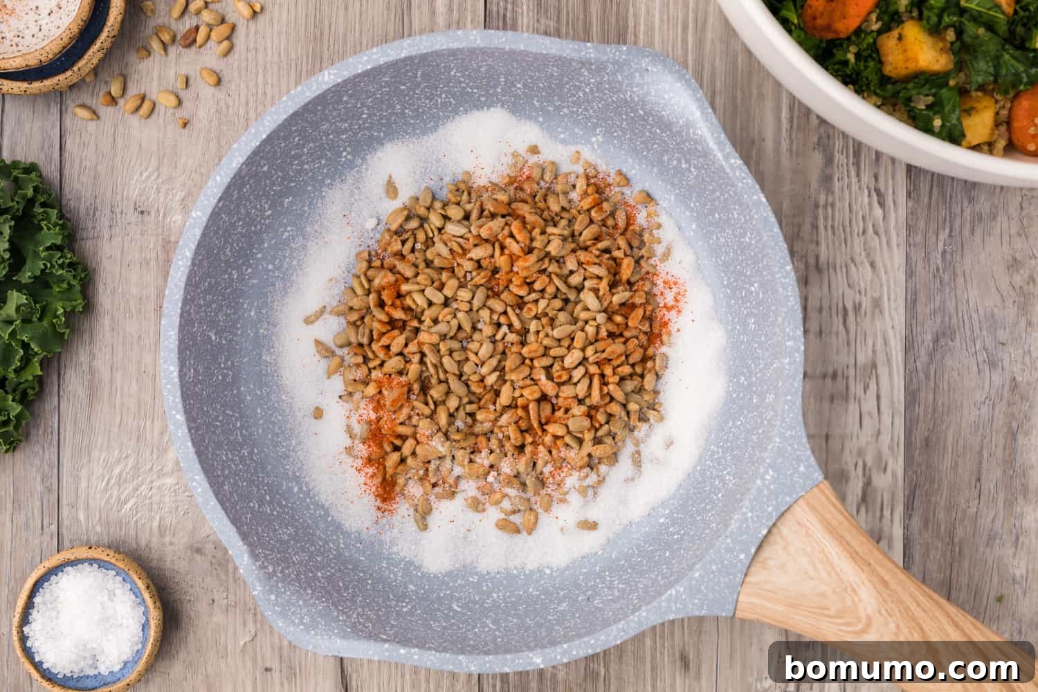 Raw sunflower seeds, sugar, cayenne pepper, and salt in a small skillet before candying.