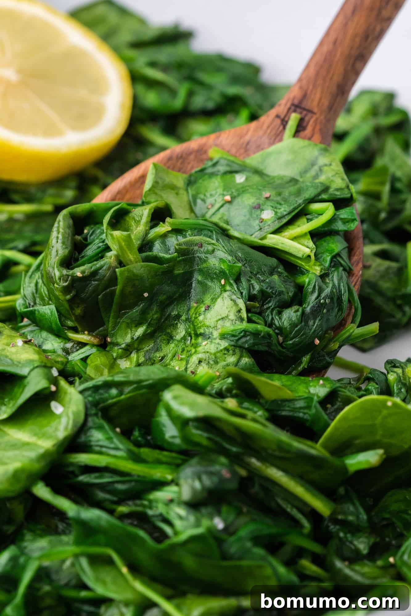 Pan-Seared Spinach Sensation 2 Vibrantly green sautéed spinach resting in a large skillet, ready to be served, with a rustic wooden spoon nearby.