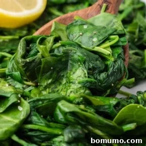 Sautéed spinach and a wooden spoon, showcasing the delicious side dish.