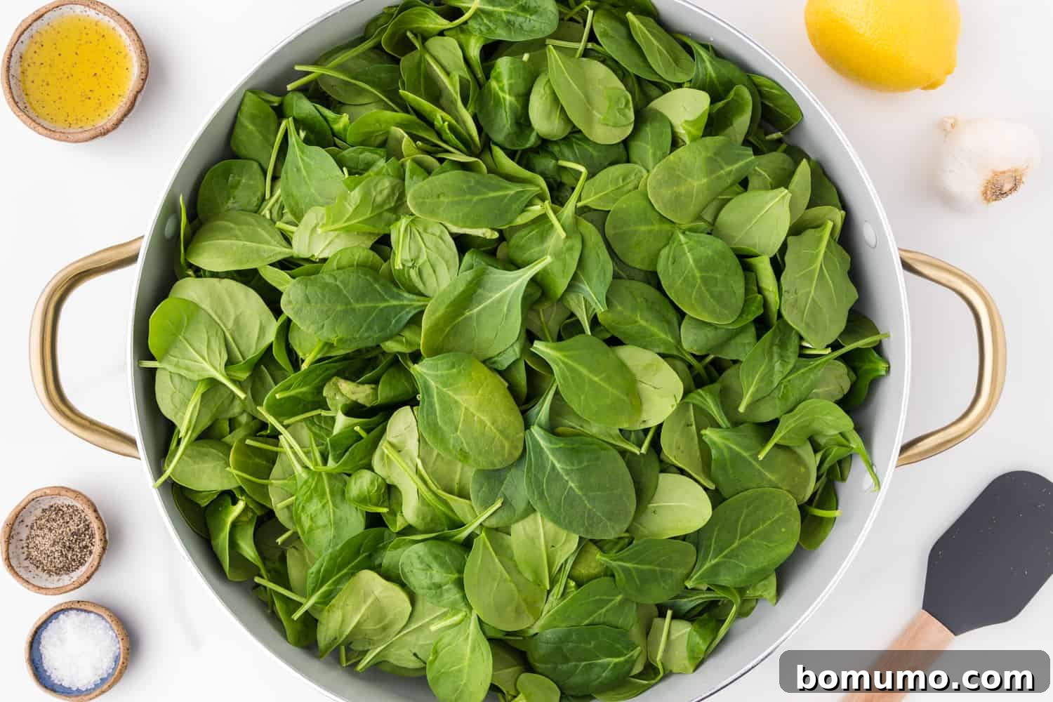 Pan-Seared Spinach Sensation 5 Fresh, uncooked spinach leaves piled high in a large skillet, ready to be sautéed.