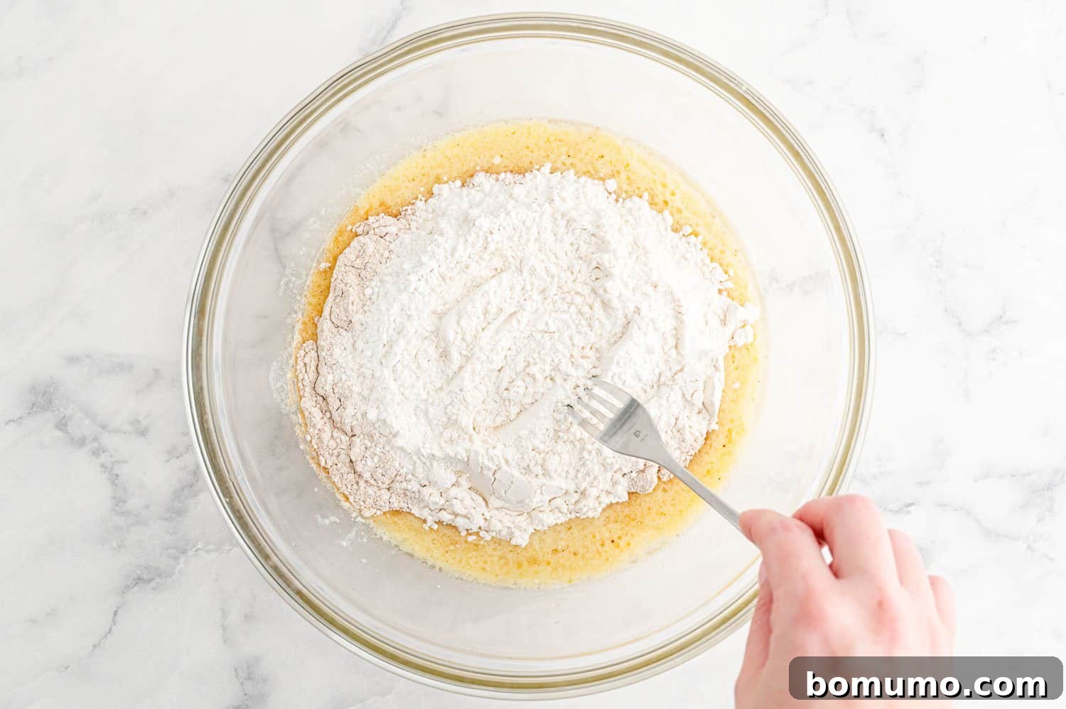 The dry ingredients for the muffins, including flours, baking powder, and salt, being lightly mixed together before adding to the wet mixture.